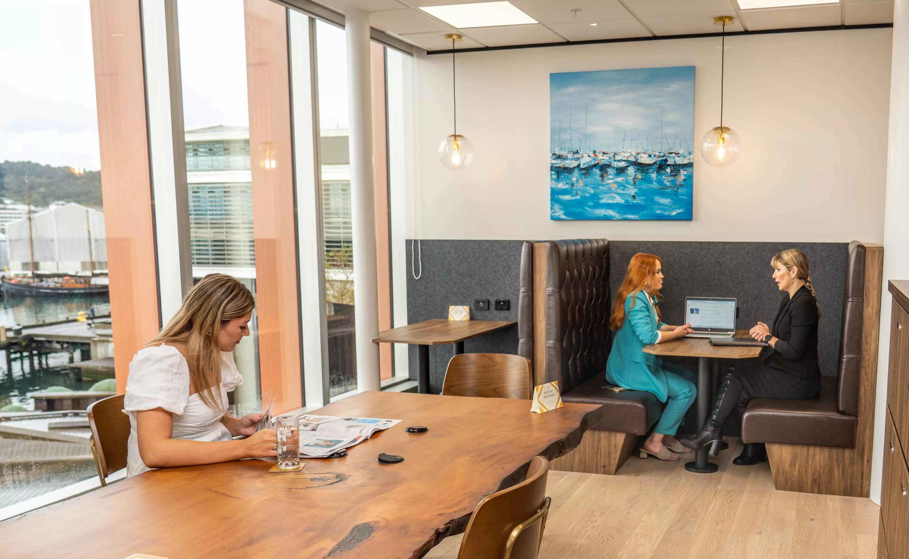 Clients working in a modern coworking shared space on a long table with great booths in Servcorp Bell Gully Building, Wellington