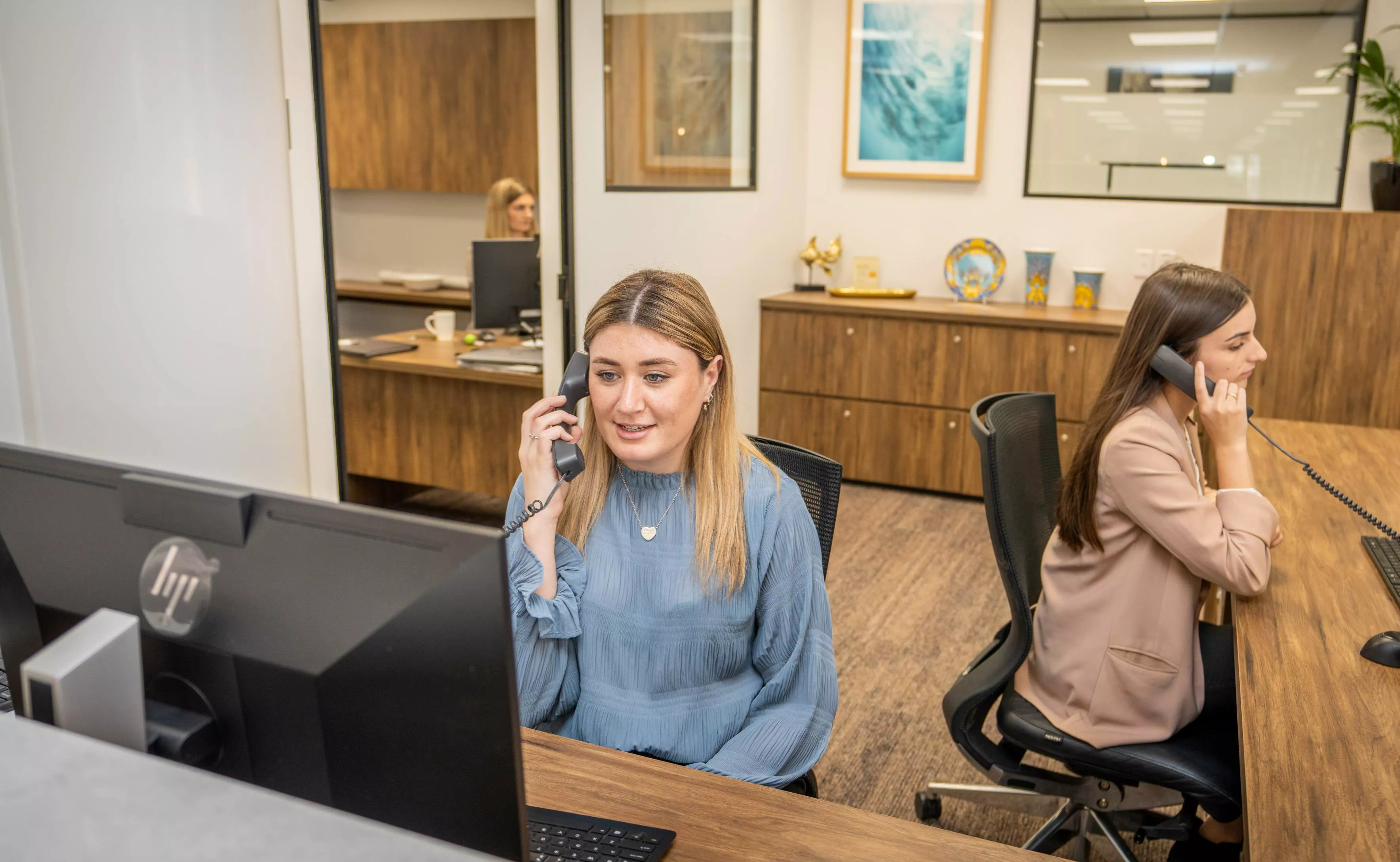 Close on dedicated receptionists helping clients in the modern coworking space of Servcorp