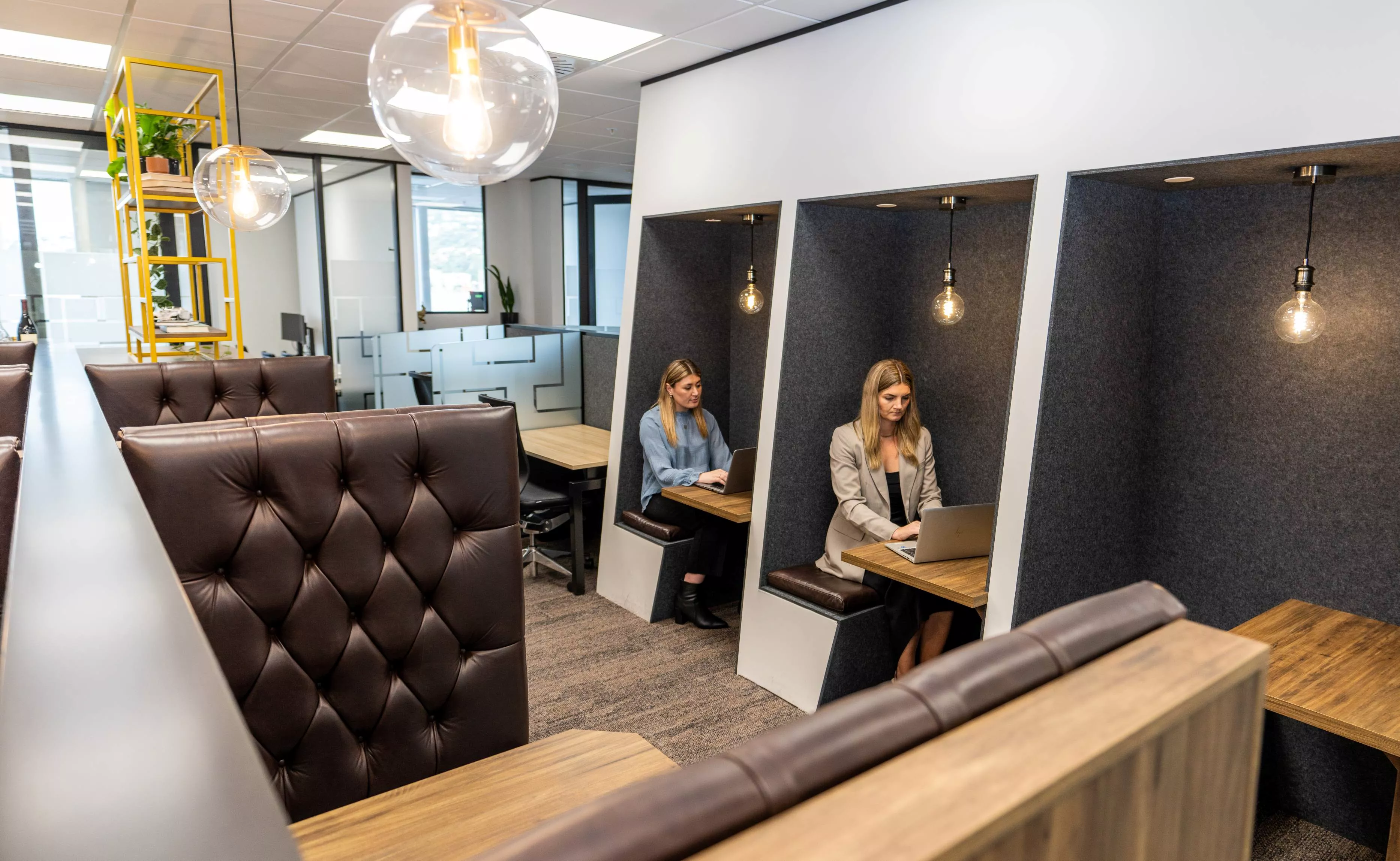 Close on clients working in the coworking lounge booths in Servcorp Bell Gully Building, Wellington