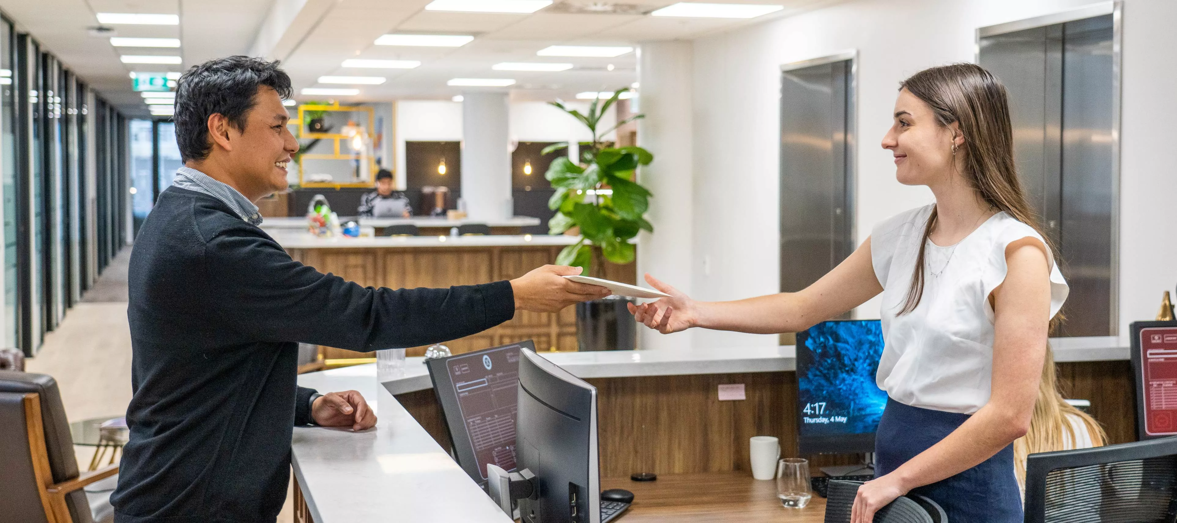 A dedicated receptionist helping a client by delivering a parcel in the modern coworking space of Servcorp Bell Gully Building, Wellington