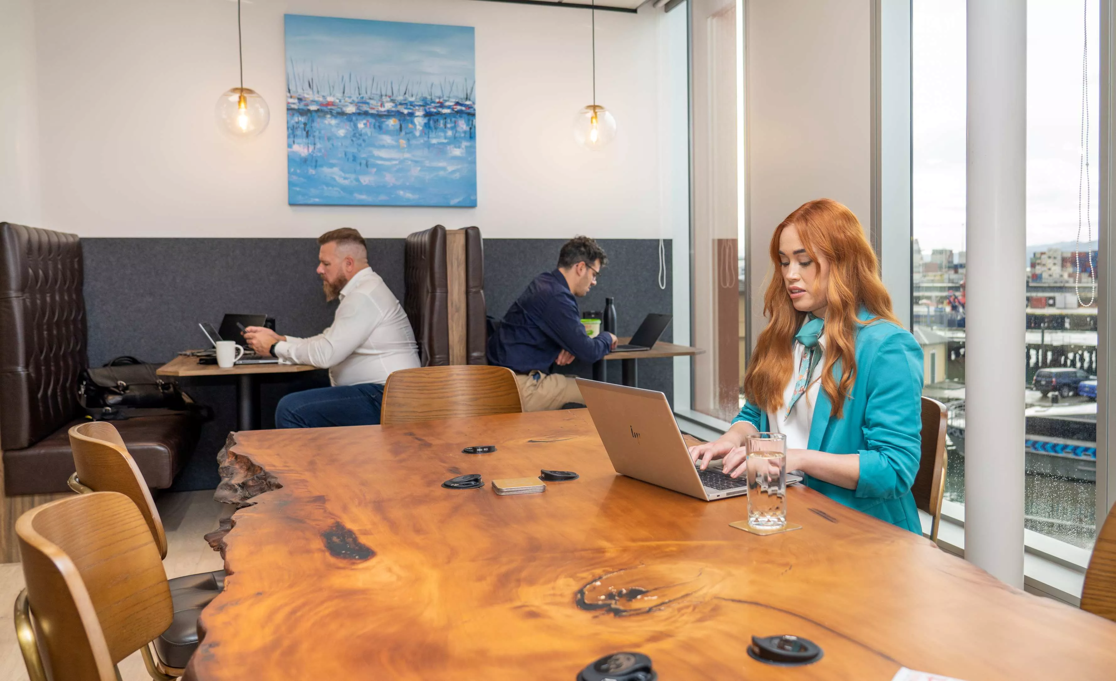 Clients working in a modern coworking shared space on a long table with great booths and nice views in Servcorp Bell Gully Building, Wellington