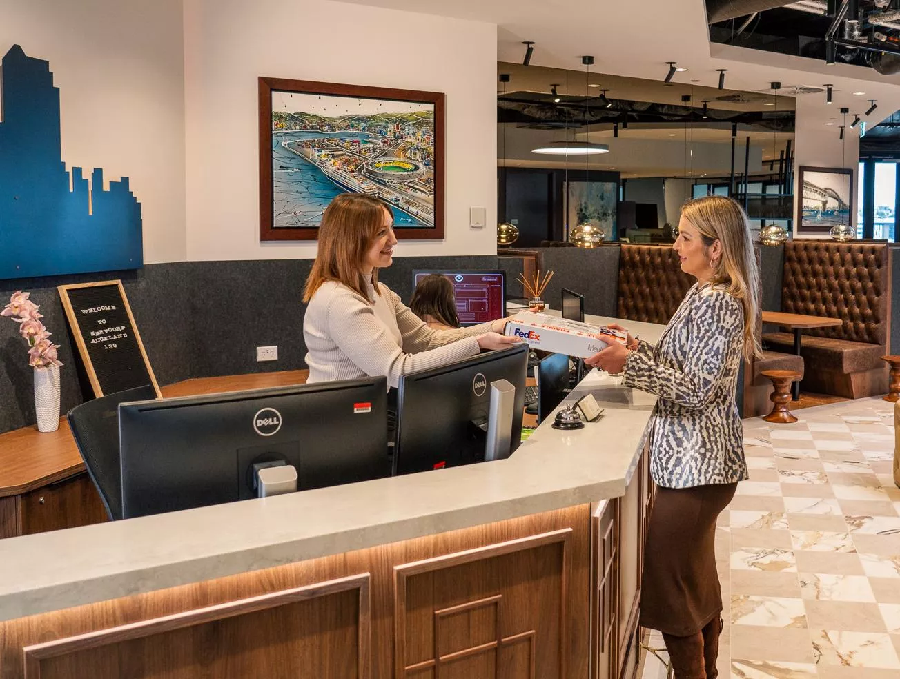 Dedicated receptionists helping a client, delivering a parcel in the modern coworking space of Servcorp 139 Quay Street, Auckland