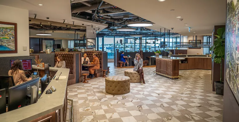 Clients working in a modern coworking shared space with dedicated receptionist and with surrounding booths in Servcorp 139 Quay Street, Auckland